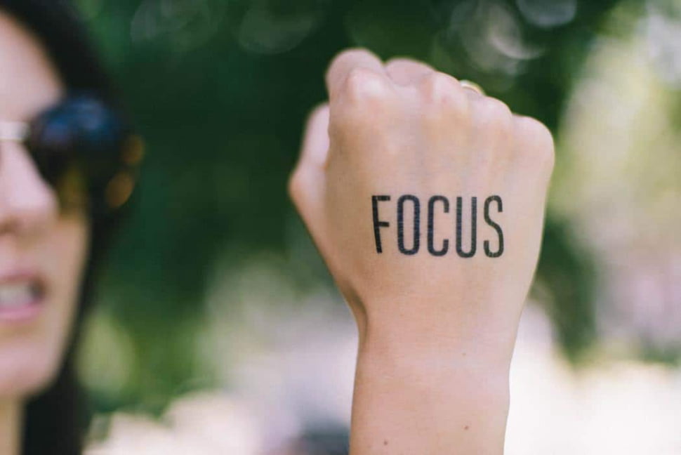 A female has written the word focus on her hand.