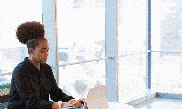 A woman of color sits at her desk and watches how her content goes to the #1 position in Google search results.